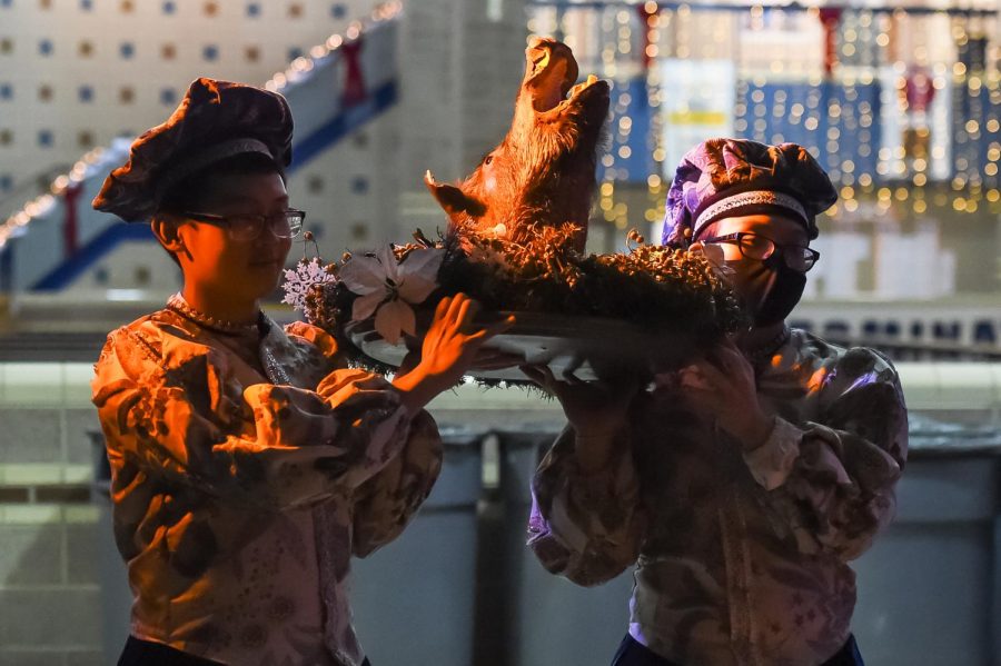 Senior Huy Bui and junior George Bui carry in the wild boar at the Madrigal Dinner.