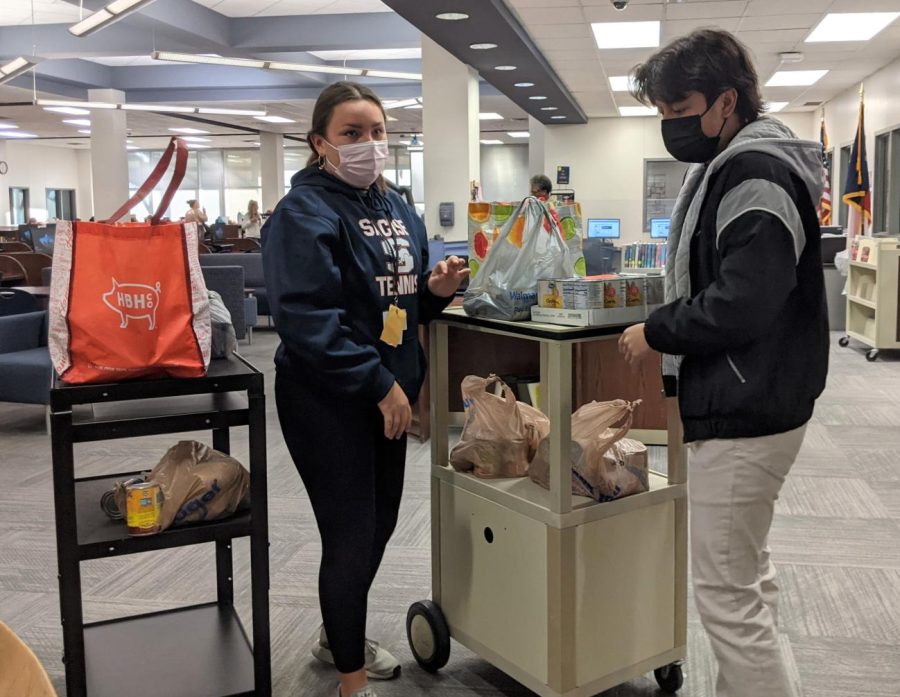 Student council members junior Brynna Olalde Taylor and senior Andy Nguyen move canned goods downstairs for the final donation.