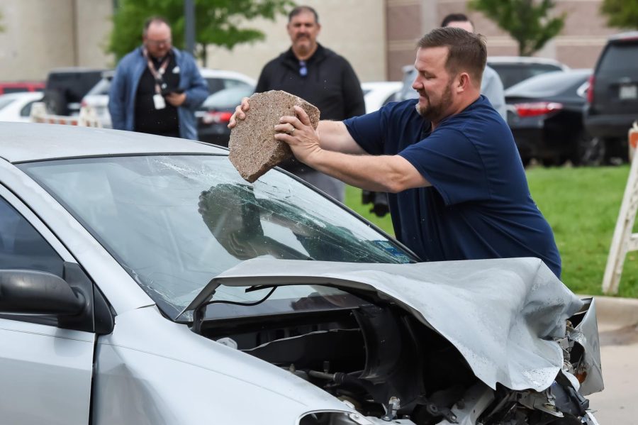 Before students arrived to watch Shattered Dreams, theatre teacher Joe Murdock breaks the windshield to create a more realistic traffic accident scene.
