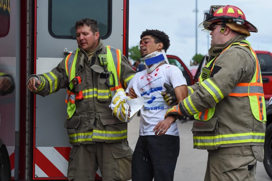 After assessing his injuries, senior Jojo Adoboe is helped into an ambulance by members of the Sachse Fire Department.
